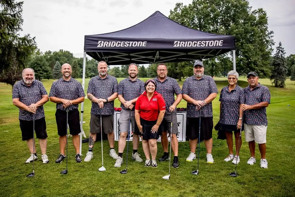 A team posing under a tent at the Chamber golf outing